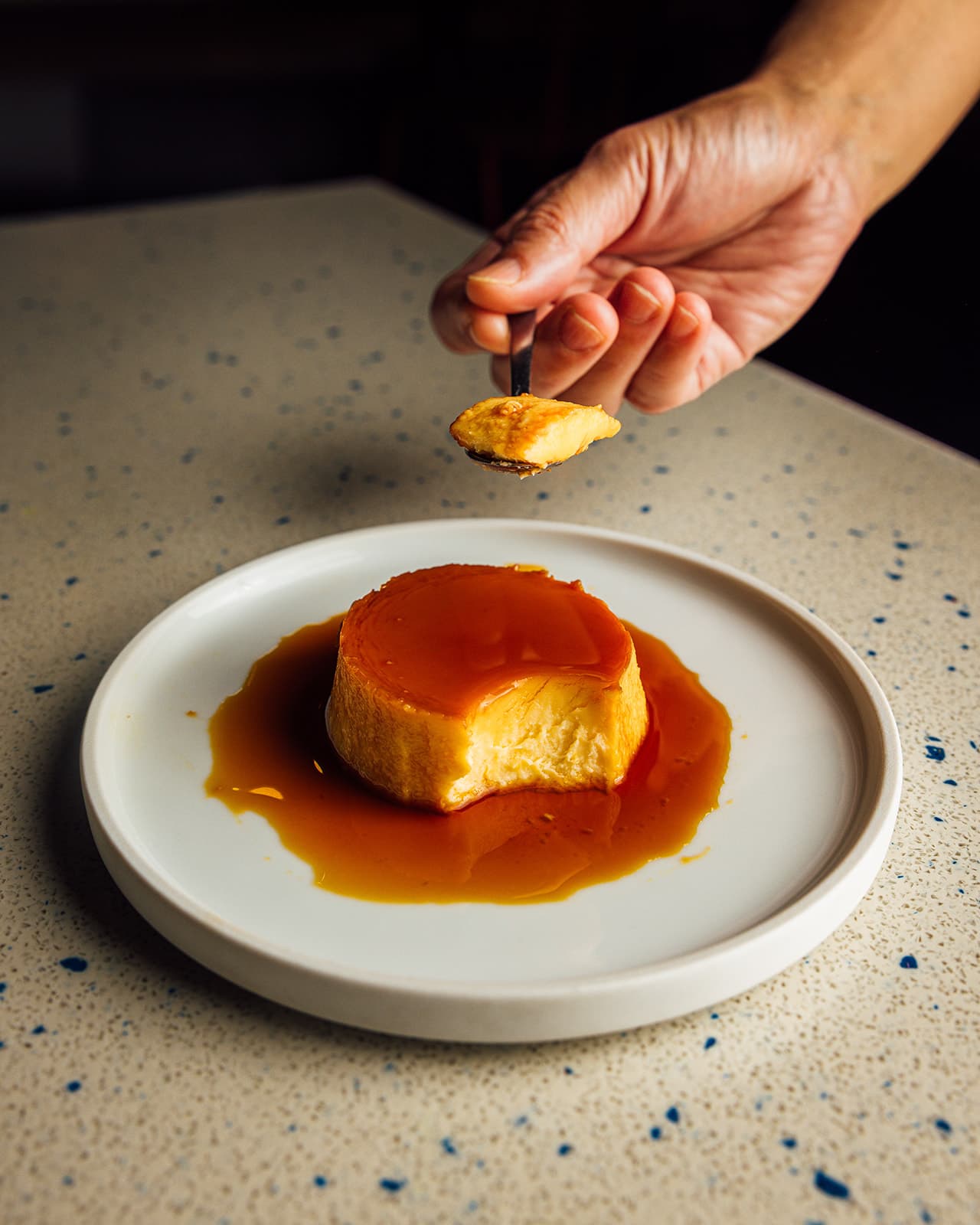 A spoonful of leche flan over a plate of caramel